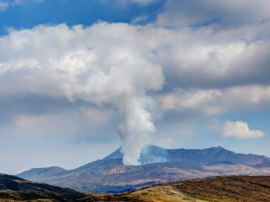 Japan's active volcano Mount Aso erupting with white smoke  clipart
