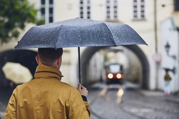 若い男が雨の中歩いて傘を保持しています プラハ チェコスロバキア共和国の古い街 — ストック写真