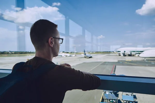 在机场等候的年轻乘客 透过窗户看飞机 — 图库照片