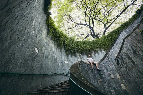 孤独的人坐在螺旋楼梯从地下走道在新加坡 — 图库照片