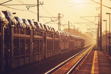 Yük treni ile yeni araçların demiryolu İstasyonu güneş doğarken commuting.