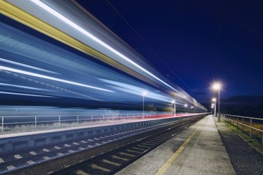 Geceleri tren istasyonuna gidip yolcu treni ışık yollar.