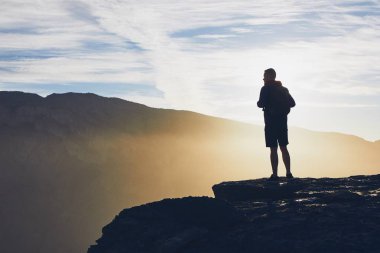 Gündoğumu, uçurumun kenarında genç turist silüeti. Jebel Akhdar, Grand Canyon Umman. 