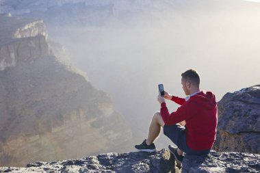 Gevşeme dağlarda. Genç adam cep telefonuyla fotoğraf çekme. Jebel Akhdar, Grand Canyon Umman.