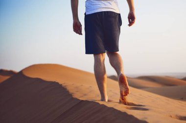 Kumul üzerine yürüyen genç adam. Wahiba Sands Umman.