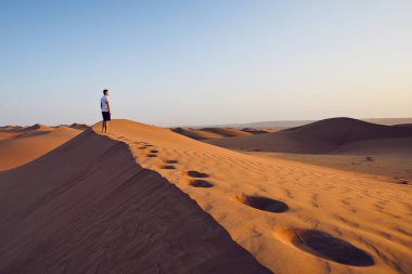 Genç kumul üzerinde duran ve manzaraya bakarak adam. Çöl Wahiba Sands Umman.