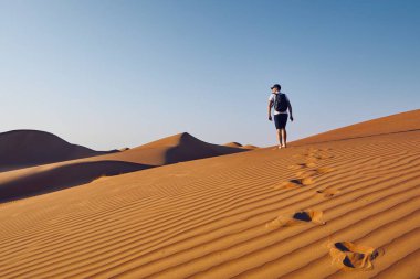 Genç Turizm kumul üzerinde yürüyen sırt çantası ile. Çöl Wahiba Sands Umman.