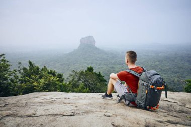 Sırt çantası Sigiriya Rock (Unesco Dünya Mirası) karşı olan genç adam. Sri Lanka Pidurangala Rock görünümünden.