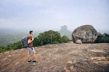 Sırt çantası Sigiriya Rock (Unesco Dünya Mirası) karşı olan genç adam. Sri Lanka Pidurangala Rock görünümünden.
