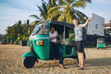 Tuk tuk sürücüsü ile yolcu karşı Sri Lanka kum plaj.
