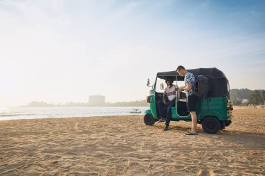 Tuk tuk sürücüsü ile yolcu kum plaj ve deniz Sri Lanka karşı.