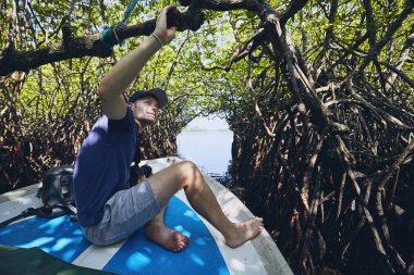 Young man during boat trip through mangrove forest in Sri Lanka. clipart