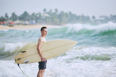 Sörfçü portresi. Kumsalda Surfboard holding genç adam. Tangalle, Sri Lanka.