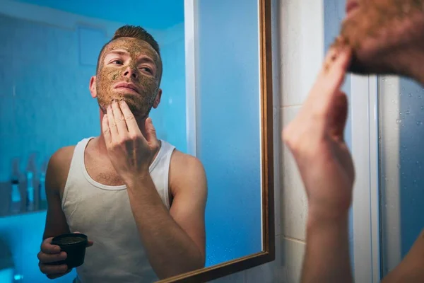 Ung Man Som Applicerar Ansiktsmask Framför Spegeln Badrummet Teman Hudvård — Stockfoto