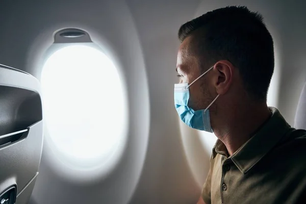 飛行中に飛行機の中で顔マスクをしている男 テーマ新しい通常 コロナウイルスや個人的な保護 — ストック写真