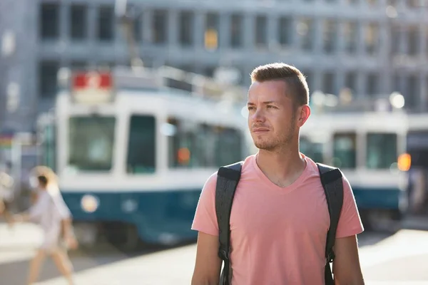 若い男はトラムの駅に対して忙しい街の通りを歩いています スイスのチューリッヒ — ストック写真