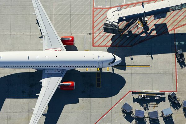 Aerial view of airport. Airplane is taxiing to gate of terminal.