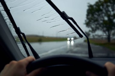 Şiddetli yağmurda araba kullanmak. Kavşaktaki trafiğe karşı arabanın ön camında yağmur damlaları.