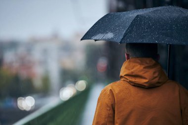 Şiddetli yağmur altında şemsiyeli genç adam köprüde yürüyor. Çek Cumhuriyeti Prag 'da Hüzünlü Gün
