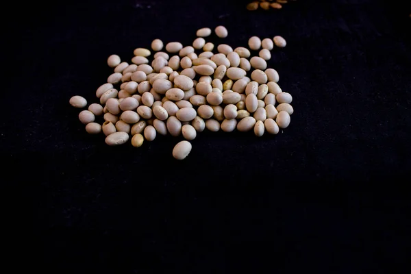 Beyaz fasulye tabakları, turuncu mercimek ve sarı bezelyeler koyu bir arkaplanda duruyor.,