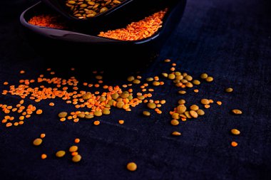 Beyaz fasulye tabakları, turuncu mercimek ve sarı bezelyeler koyu bir arkaplanda duruyor.,