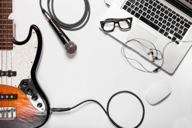 Ofis resepsiyon arka plan. Şık minimalist çalışma alanı ile bir dizüstü bilgisayar, gitar, mikrofon ve düz bir stil gözlük. Beyaz arka plan. Yukarıdan görüntülemek.
