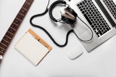 Şık minimalist çalışma alanı bir dizüstü bilgisayar, kulaklık, bir gitar, bir düz stil içinde a defter. Beyaz arka plan. Yukarıdan görüntülemek.