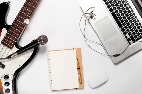 Şık minimalist çalışma alanı bir dizüstü bilgisayar, kulaklık, bir gitar, bir düz stil içinde a defter. Beyaz arka plan. Yukarıdan görüntülemek.