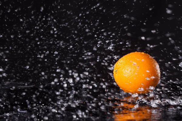 Fresh orange on black background with streaming water on it