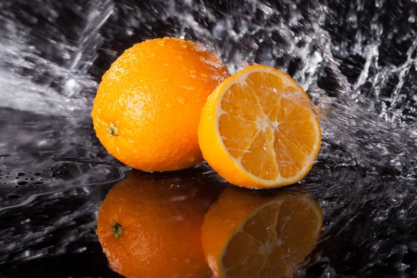 Fresh orange on black background with streaming water on it