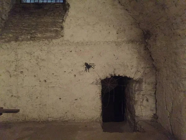 Close-up of hole in stone wall with painted spider in ancient dungeon