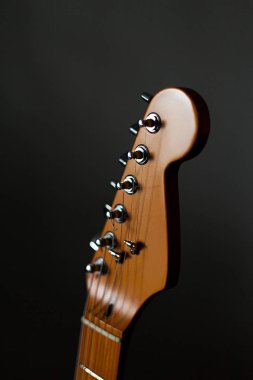 Headstock of the six string classic electric guitar on dark  background  clipart