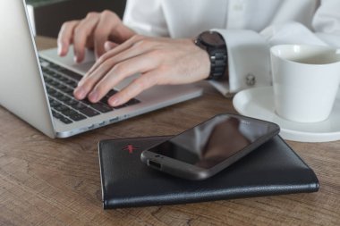 Havaalanı terminal kafe, kahve fincanı, pasaport ve masada akıllı telefon dizüstü bilgisayar kullanarak seyahat işadamı