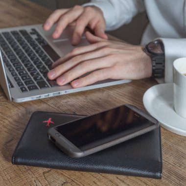 Havaalanı terminal kafe, kahve fincanı, pasaport ve masada akıllı telefon dizüstü bilgisayar kullanarak seyahat işadamı