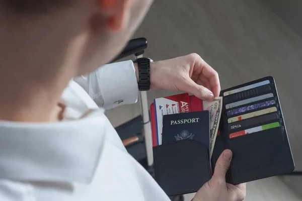 Havaalanı terminalinde pasaport, kredi kartı ve bileti çantada kontrol edecek erkek yolcu