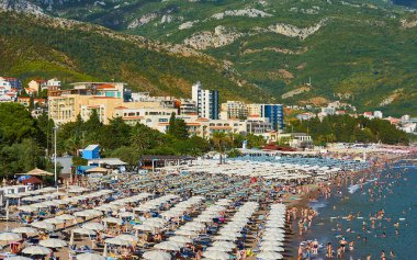 Karadağ, Becici - 12 Ağustos 2017: Becici tatil beldesinin popüler plajı plaj şemsiyeleri ve turist kalabalıklarıyla dolu
