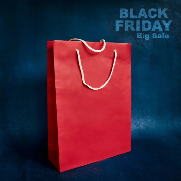Black Friday. Red gift paper bag on blue background