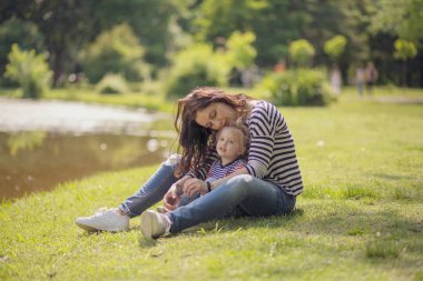 Parktaki mutlu anne ve kız. Aile hayatı olan güzel doğa manzarası. Mutlu bir aile yeşil çimlerin üzerinde birlikte dinleniyor, dışarıda eğleniyor. Aile hayatında mutluluk ve uyum.