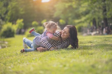 Parktaki mutlu anne ve kız. Aile hayatı olan güzel doğa manzarası. Mutlu bir aile yeşil çimlerin üzerinde birlikte dinleniyor, dışarıda eğleniyor. Aile hayatında mutluluk ve uyum..