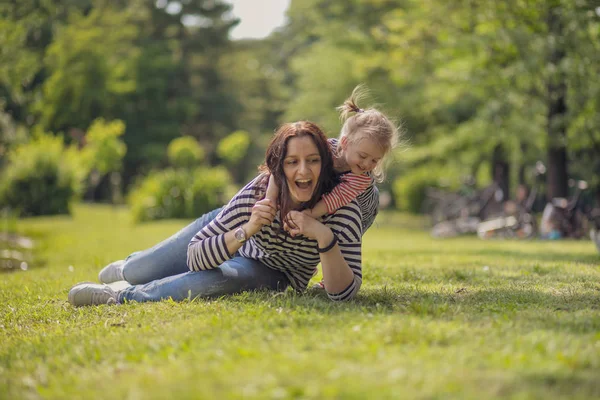 Parktaki mutlu anne ve kız. Aile hayatı olan güzel doğa manzarası. Mutlu bir aile yeşil çimlerin üzerinde birlikte dinleniyor, dışarıda eğleniyor. Aile hayatında mutluluk ve uyum..