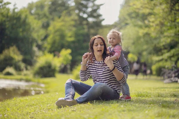 Parktaki mutlu anne ve kız. Aile hayatı olan güzel doğa manzarası. Mutlu bir aile yeşil çimlerin üzerinde birlikte dinleniyor, dışarıda eğleniyor. Aile hayatında mutluluk ve uyum..