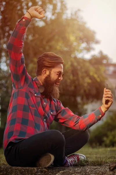 Happy hipster taking selfie. Outdoor portrait of happy young man.