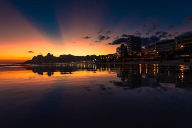 Günbatımı görünümünde suya yansıtan gökyüzünde güneş ışınları ile Ipanema Plajı