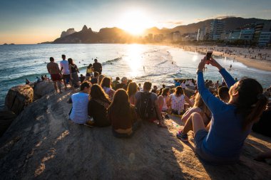Rio De Janeiro, Brezilya - 18 Ağustos 2018: Arpoador kayalıklarda oturan her yerinde ve güzel gün batımı zevk insanlar.