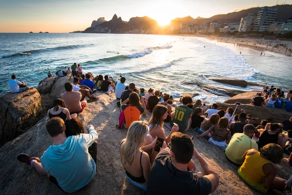 stock image RIO DE JANEIRO, BRAZIL - AUGUST 18TH, 2018: People sitting all around on Arpoador rock and enjoying beautiful sunset.