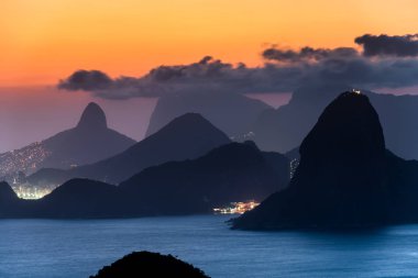 CopacabanaPlajı ışıklar gece ve Rio de Janeiro Dağları ile görünümünü