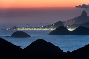 CopacabanaPlajı ışıklar gece ve Rio de Janeiro Dağları ile görünümünü