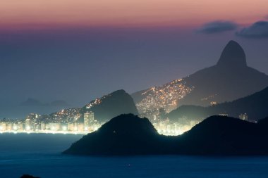 CopacabanaPlajı ışıklar gece ve Rio de Janeiro Dağları ile görünümünü
