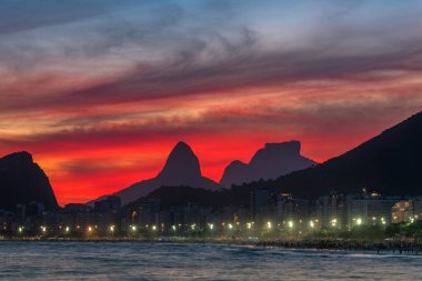 Gün Batımından Hemen Sonra Güzel Kırmızı Gökyüzü ile Copacabana Plajı Gece Görünümü, ve Ufukdağlar, Rio de Janeiro, Brezilya