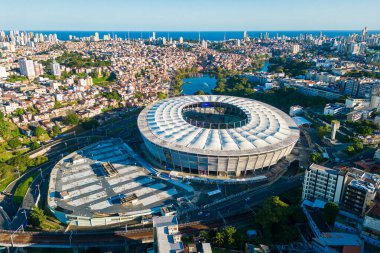 Salvador, Brazil - July 30, 2025: Aerial view of Fonte Nova Arena football stadium with city skyline and ocean in the horizon.